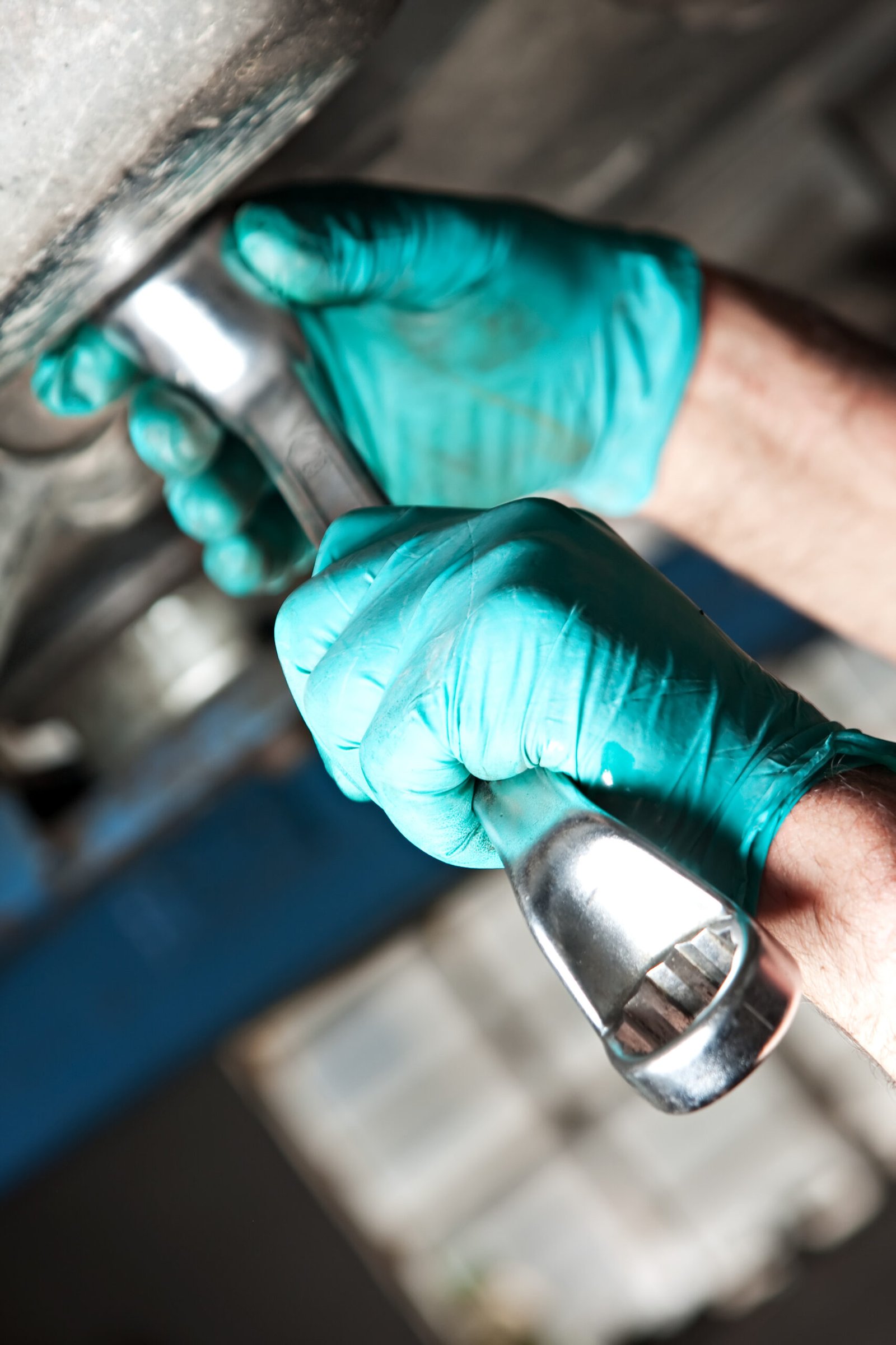 Mécanicien utilisant une clé pour réparer une pièce sous un véhicule.