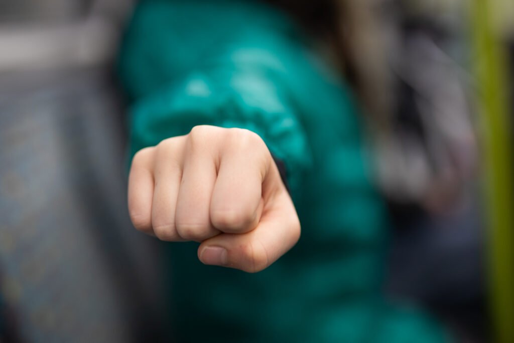 Main avec poing fermé tendu en avant, symbole de force et détermination.
