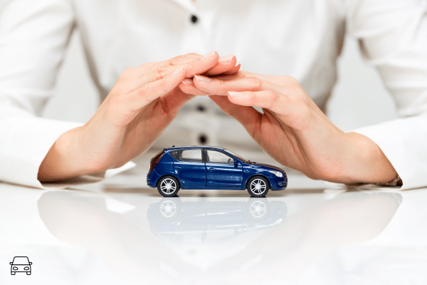 Mains protégeant une petite voiture, symbole de la protection juridique de l'acheteur face à un vice caché sur un véhicule acheté à l'étranger