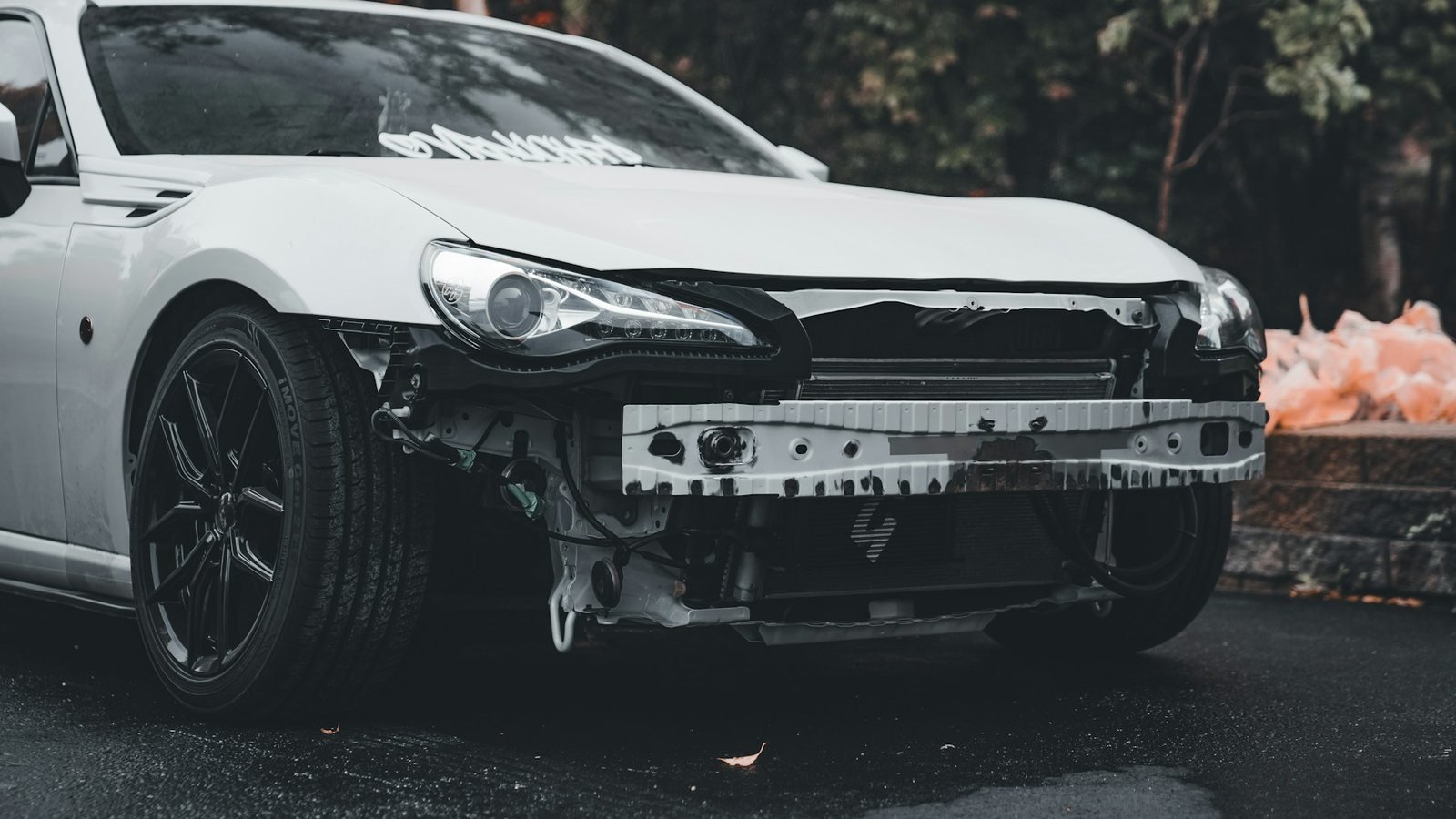 Voiture blanche au pare-chocs avant arraché, dommages réparables typiques d'un véhicule classé économiquement irréparable